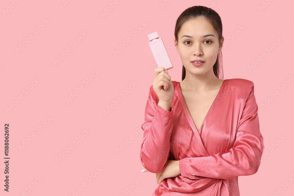 Beautiful young Asian woman with bottle of perfume on pink background Beautiful young Asian woman with bottle of perfume on pink background
