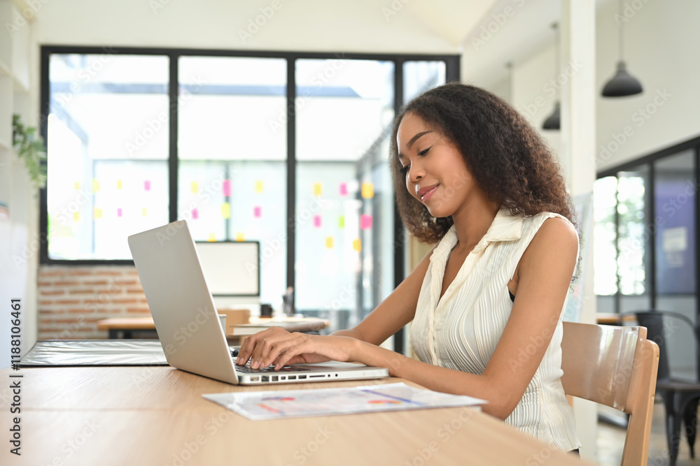 Confident businesswoman working on her laptop in a bright, modern office space Confident businesswoman working on her laptop in a bright, modern office space