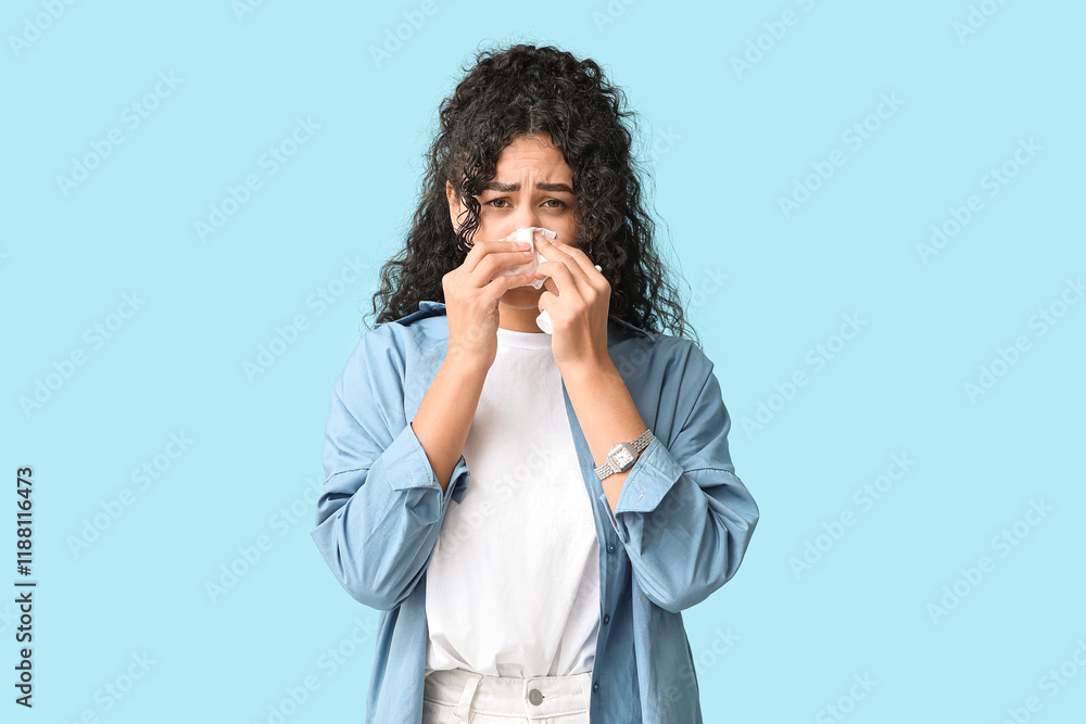 Young African-American woman with handkerchief and nasal spray suffering from allergy on blue background Young African-American woman with handkerchief and nasal spray suffering from allergy on blue background