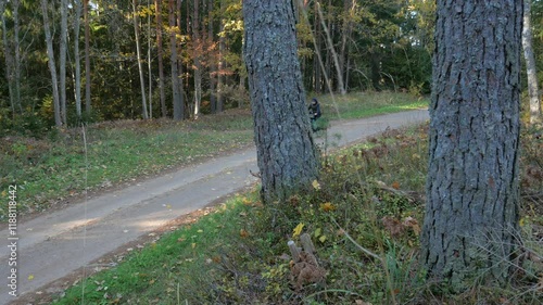 A cycling tourist riding on a path through autumn forest
