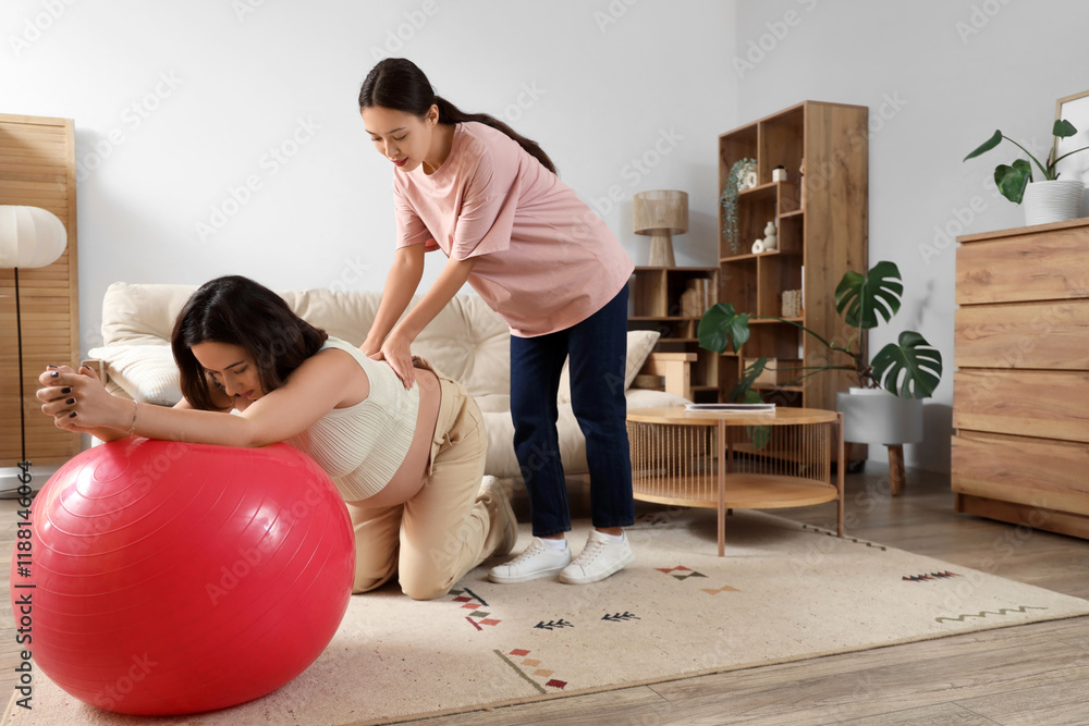 © Pixel-Shot - Young Asian doula and pregnant woman training with fitball at home © Pixel-Shot - Young Asian doula and pregnant woman training with fitball at home