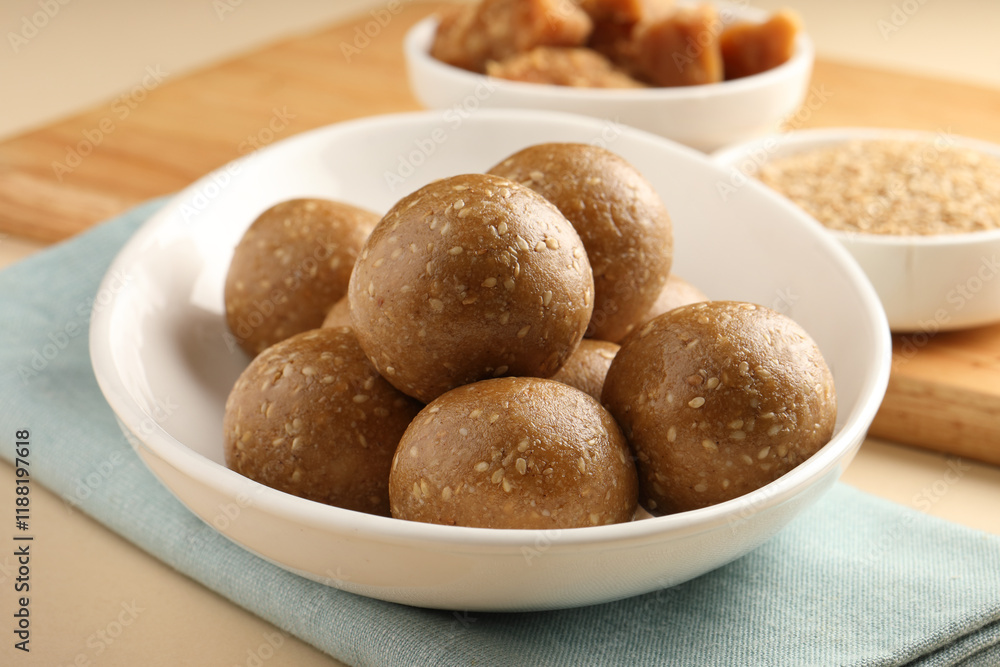 Tilgul Laddu or Til Gul balls for makar sankranti, it's a healthy food made using sesame, crushed peanuts and jaggery. served in a bowl. selective focus showing details. Tilgul Laddu or Til Gul balls for makar sankranti, it's a healthy food made using sesame, crushed peanuts and jaggery. served in a bowl. selective focus showing details.
