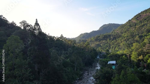 A mountain valley with a river running through it. The river is blue and the valley is lush with green trees. The scene is serene and peaceful, with the water