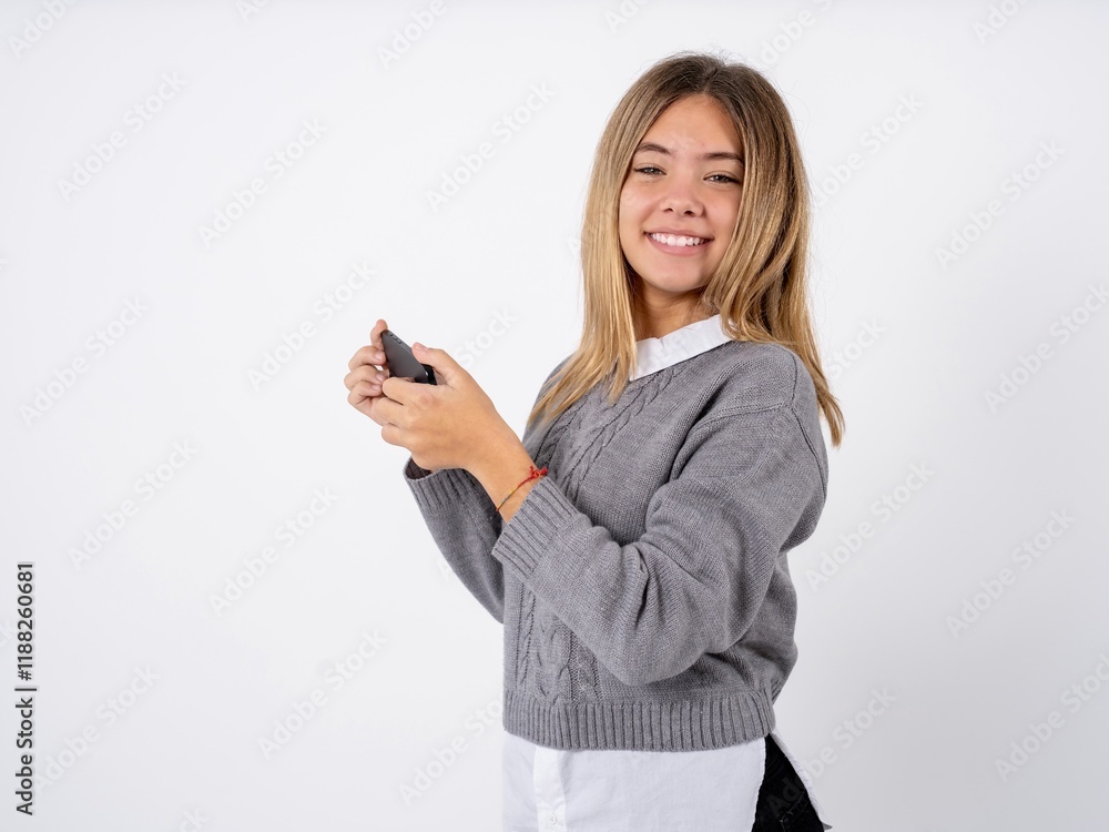 Nice addicted cheerful Beautiful teen girl wearing grey sweater using gadget playing network game Nice addicted cheerful Beautiful teen girl wearing grey sweater using gadget playing network game