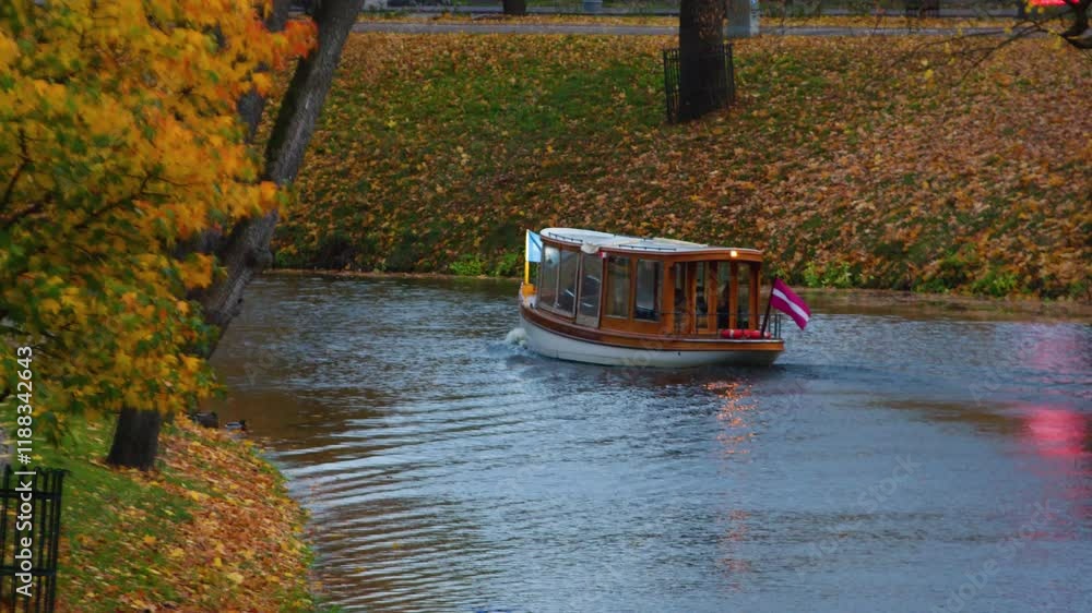 A charming white wooden boat with colorful flags cruises along a peaceful autumn canal, surrounded by vibrant golden foliage and calm waters, reflecting the seasonal beauty. A charming white wooden boat with colorful flags cruises along a peaceful autumn canal, surrounded by vibrant golden foliage and calm waters, reflecting the seasonal beauty.