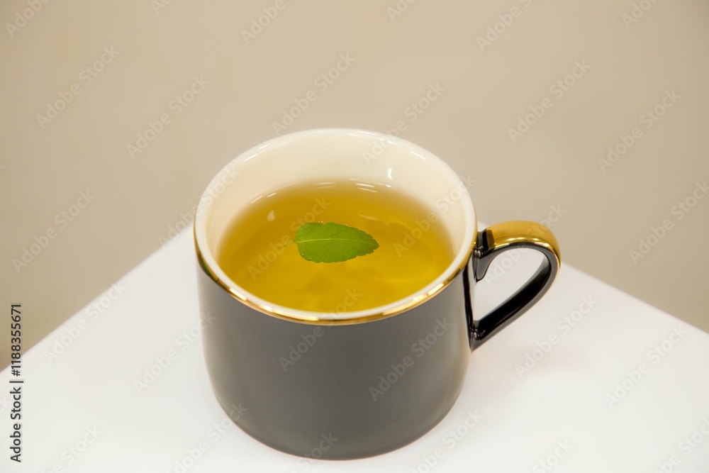 Black mug of herbal tea with green leaf Black mug of herbal tea with green leaf