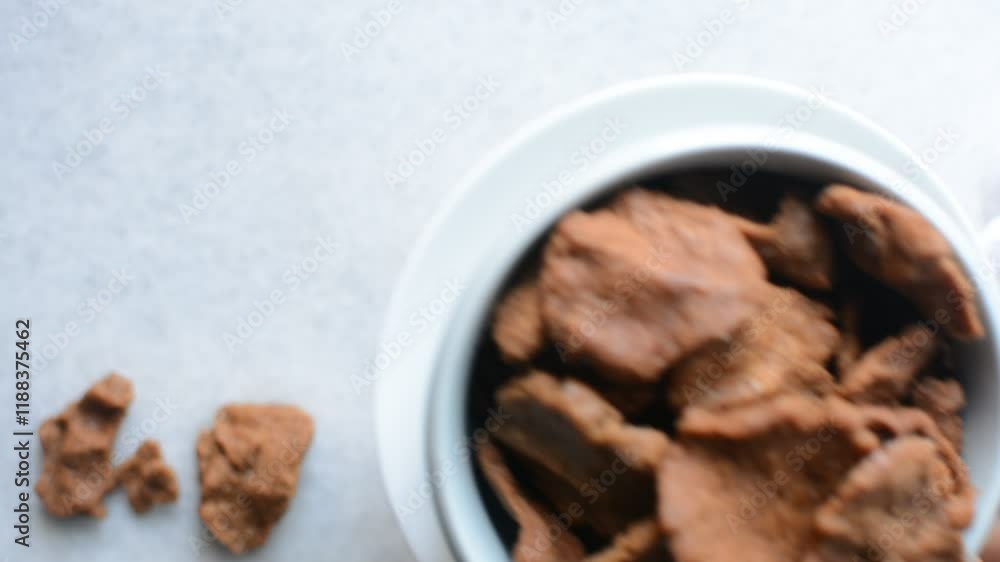 Overhead view of kuli-kuli in a white bowl, top view of nigerian groundnut cakes in a bowl, fresh homemade nigerian kulikuli in a ceramic bowl Overhead view of kuli-kuli in a white bowl, top view of nigerian groundnut cakes in a bowl, fresh homemade nigerian kulikuli in a ceramic bowl