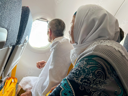 An elderly man in ihram and an elderly woman are flying in a plane for Umrah in Mecca. Flying over the Miqat.  photo