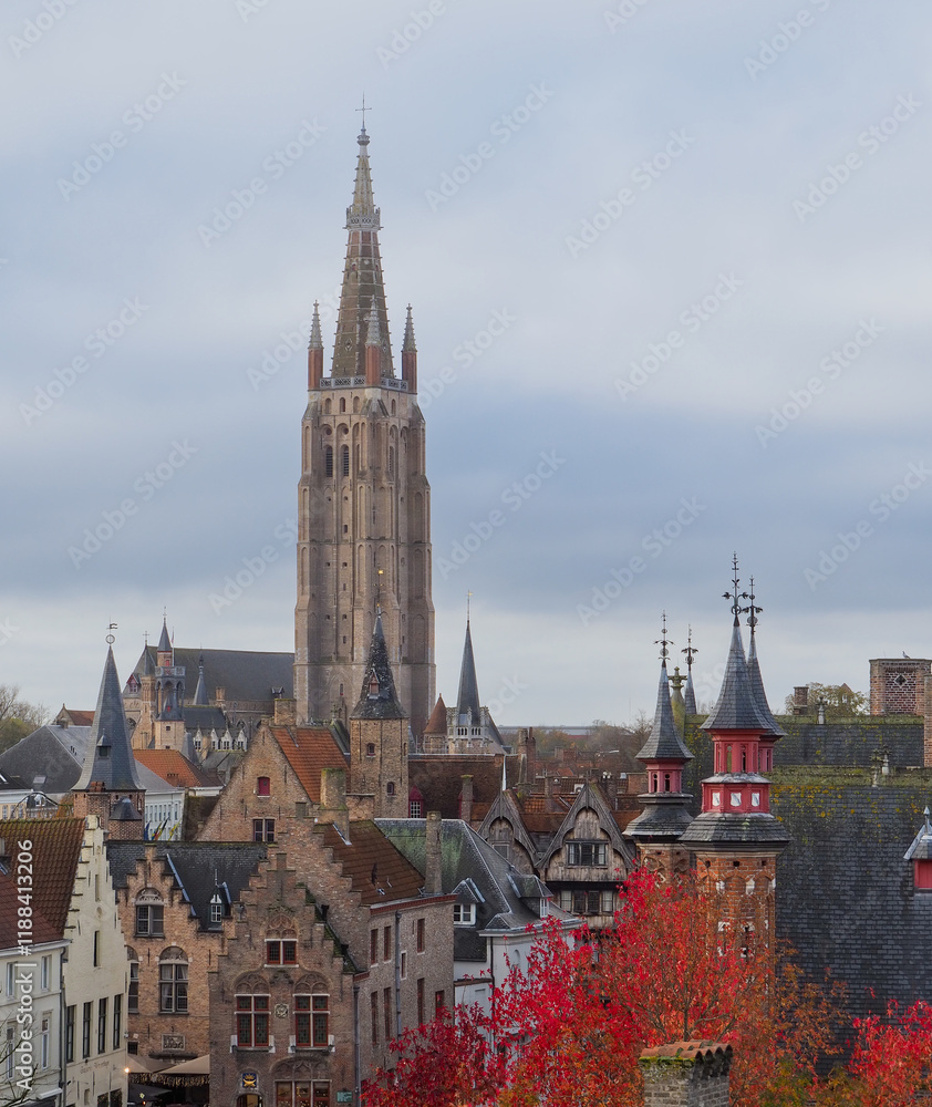 Naklejka premium A variety of pointy building spires reach for the sky on the rooftops of Bruges, Belgium skyline. 