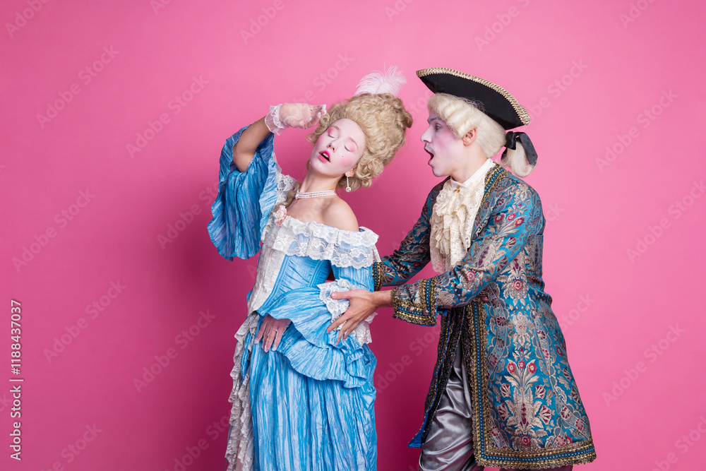Elegant couple dressed in glamorous period costumes posing humorously against a pink background. Elegant couple dressed in glamorous period costumes posing humorously against a pink background.