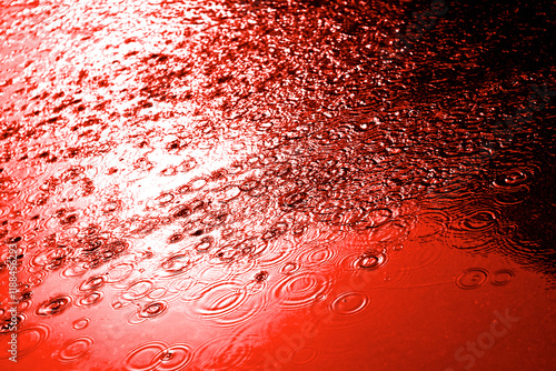 Red ocean bloody water drops background with blue sky reflection and blood circles on dark asphalt. Murder and killing. War crime. Close up.
