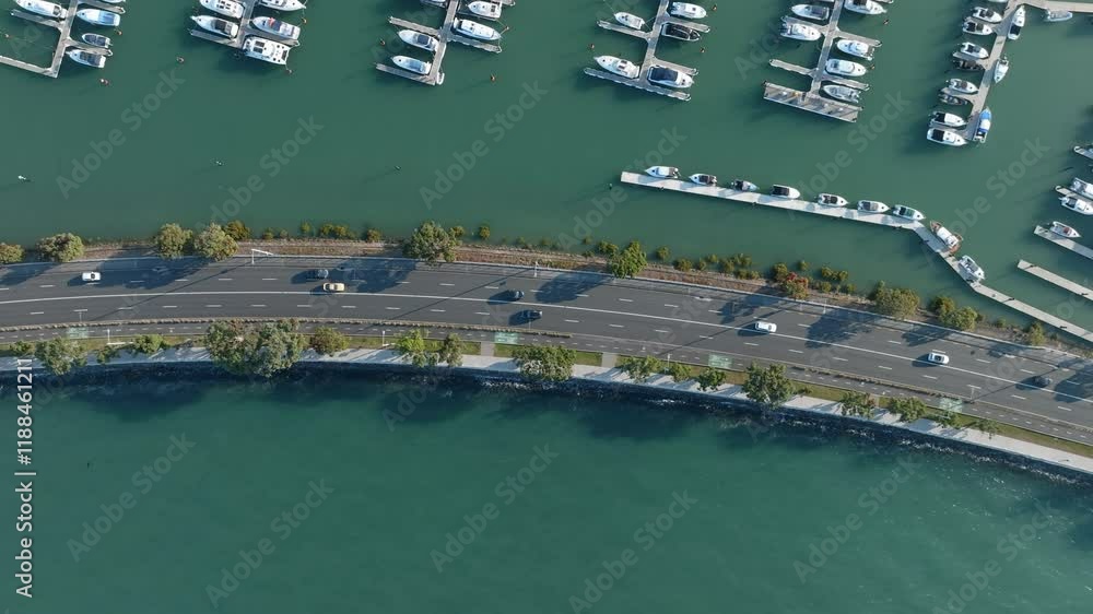 Aerial view of a marina with docked boats, a road, and cars. Urban waterfront scene. Tamaki Dr, Hobson Bay, Auckland, NZ Aerial view of a marina with docked boats, a road, and cars. Urban waterfront scene. Tamaki Dr, Hobson Bay, Auckland, NZ