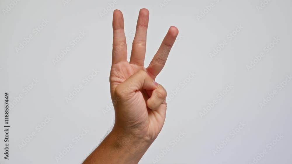 Man showing hand gesture for the number three against a plain white background