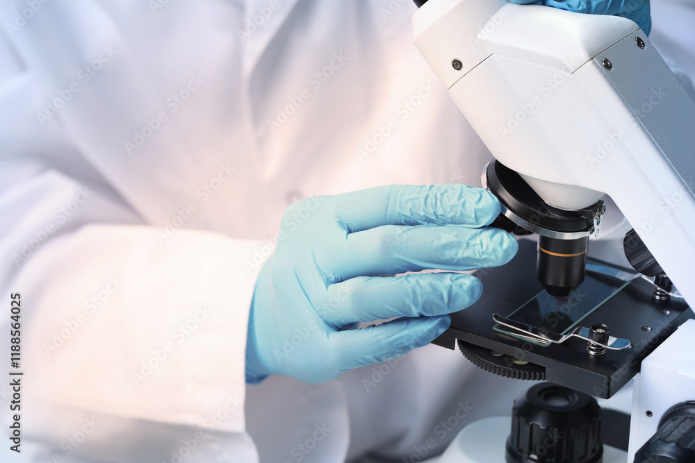 Scientist examining sample on slide under microscope, closeup Scientist examining sample on slide under microscope, closeup