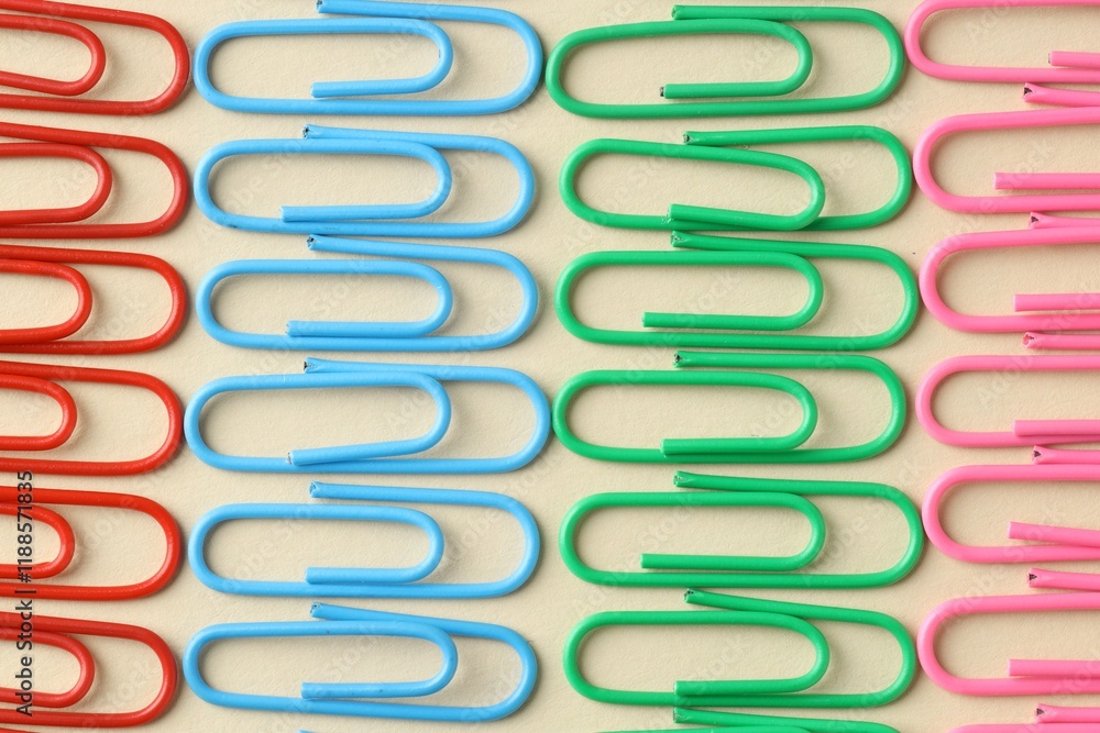 Colorful paper clips on beige background, flat lay Colorful paper clips on beige background, flat lay