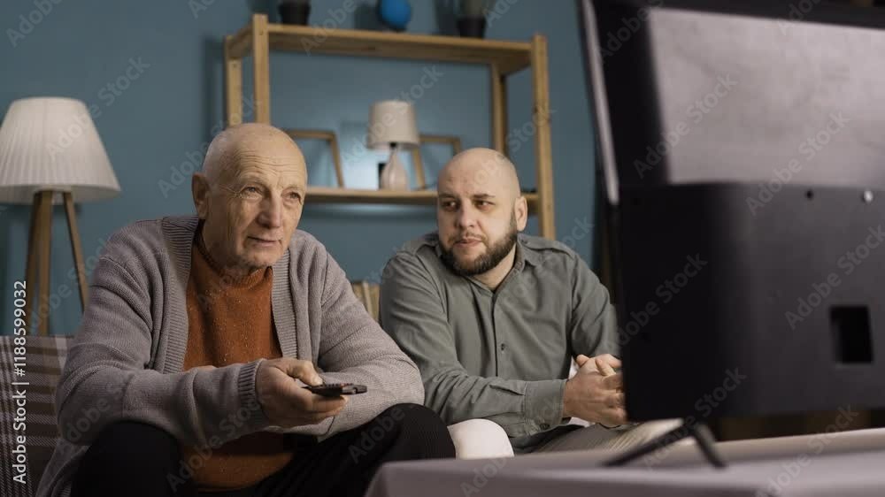 Grandfather and grandson watching TV together at home Grandfather and grandson watching TV together at home