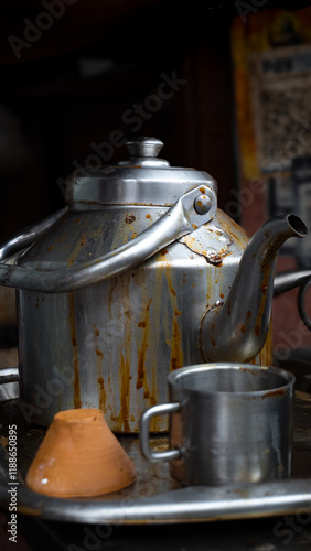 Indian tea shop, aluminum kettle covered in tea with a clay cup next to it on the metal tray. A traditional and natural way of drinking tea in India. Tea stall in the side of the road in Varanasi.