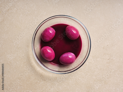 A bowl filled with rich beetroot soup surrounds several pink eggs, highlighting a traditional Ukrainian recipe. This step in the cooking process presents a vibrant and inviting dish