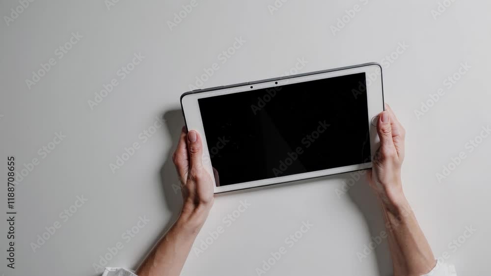 tablet held horizontally by hands, showcasing a blank screen with a clean and professional look