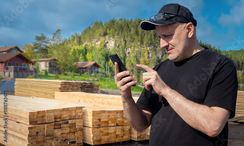 Man with phone near lumber....