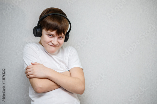 a ten year old boy looks at the camera made a face and crossed his arms over his chest. in wireless black headphones photo