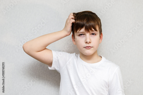 Ten year old boy scratching his head thoughtfully. Close-up portrait
