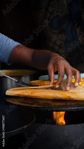 Man cooking Dosa Traditional South Indian breakfast. Concept of Indian cousin. Hand of Indian man clocking street food on the side of the road. Traditional Indian crepe. Concept Street food and travel
