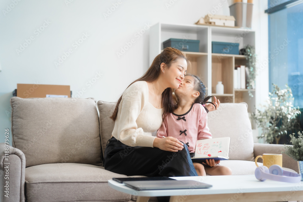 Asian young mother and her daughter sit together on the sofa in the cozy living room, working on homework at the desk, creating a warm and supportive atmosphere for learning, love, hug, mother days. Asian young mother and her daughter sit together on the sofa in the cozy living room, working on homework at the desk, creating a warm and supportive atmosphere for learning, love, hug, mother days.