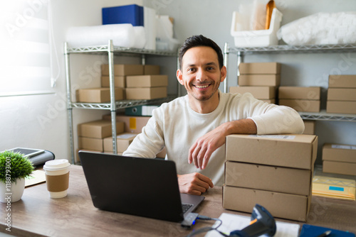 Latino entrepreneur joyfully fulfilling shipping orders from his home office with a laptop and barcode scanner