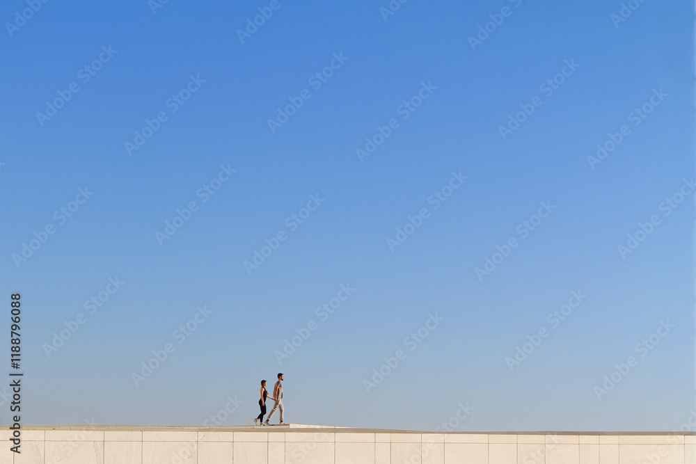 couple walking together on the building roof in front of blue sky couple walking together on the building roof in front of blue sky