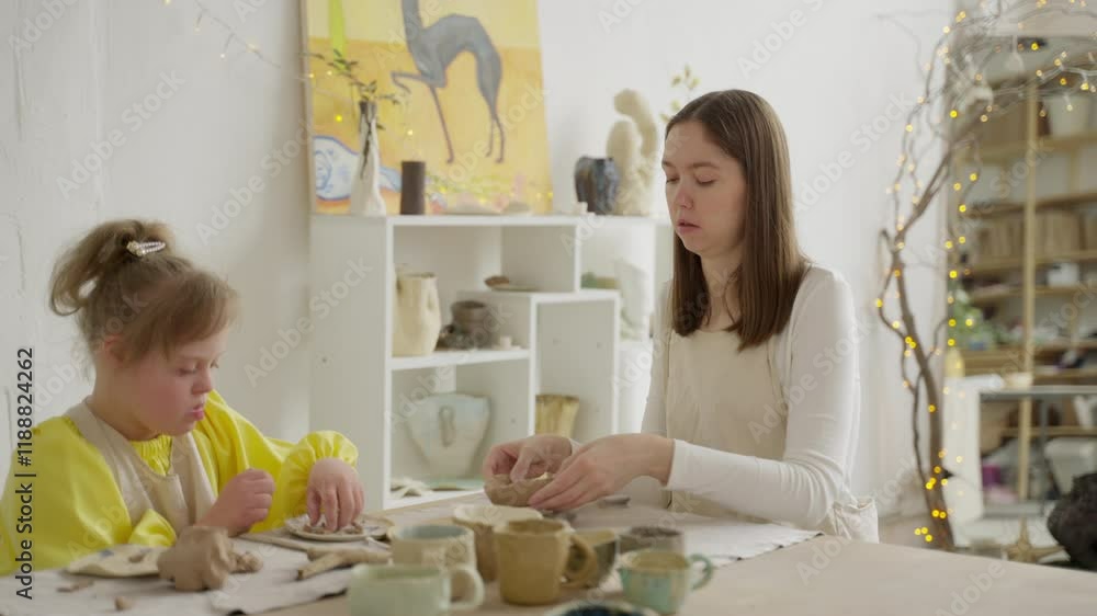 Child with Down syndrome and female instructor craft together in bright pottery studio, highlighting social inclusion. Scene underscores importance of acceptance and belonging in educational settings Child with Down syndrome and female instructor craft together in bright pottery studio, highlighting social inclusion. Scene underscores importance of acceptance and belonging in educational settings