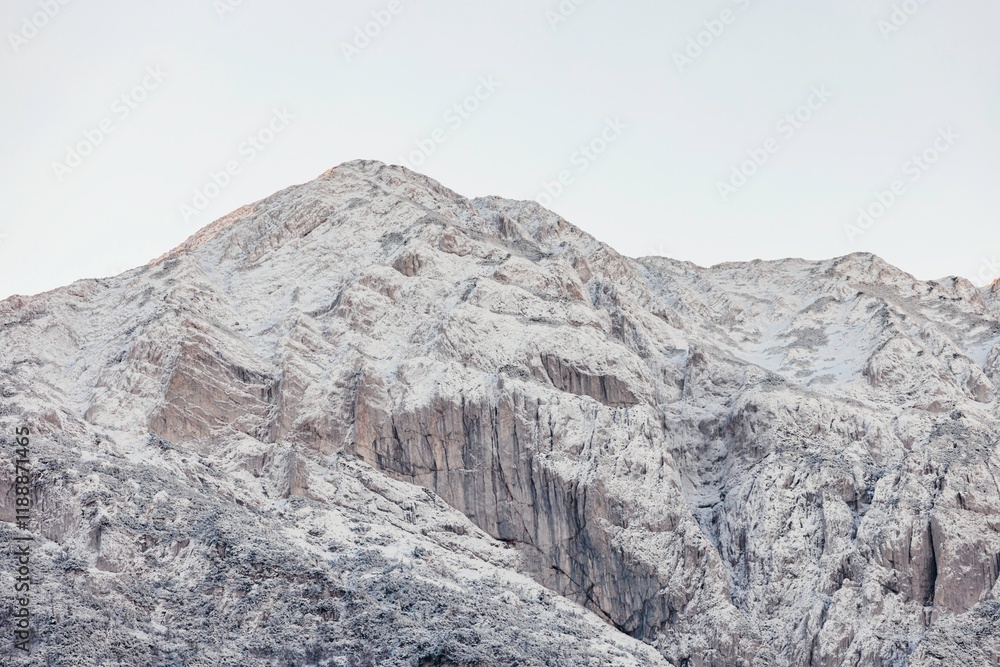 At dawn, the rugged mountain range is blanketed in fresh snow, showcasing its natural beauty. Soft sunlight reflects off the icy surfaces, creating a tranquil atmosphere At dawn, the rugged mountain range is blanketed in fresh snow, showcasing its natural beauty. Soft sunlight reflects off the icy surfaces, creating a tranquil atmosphere