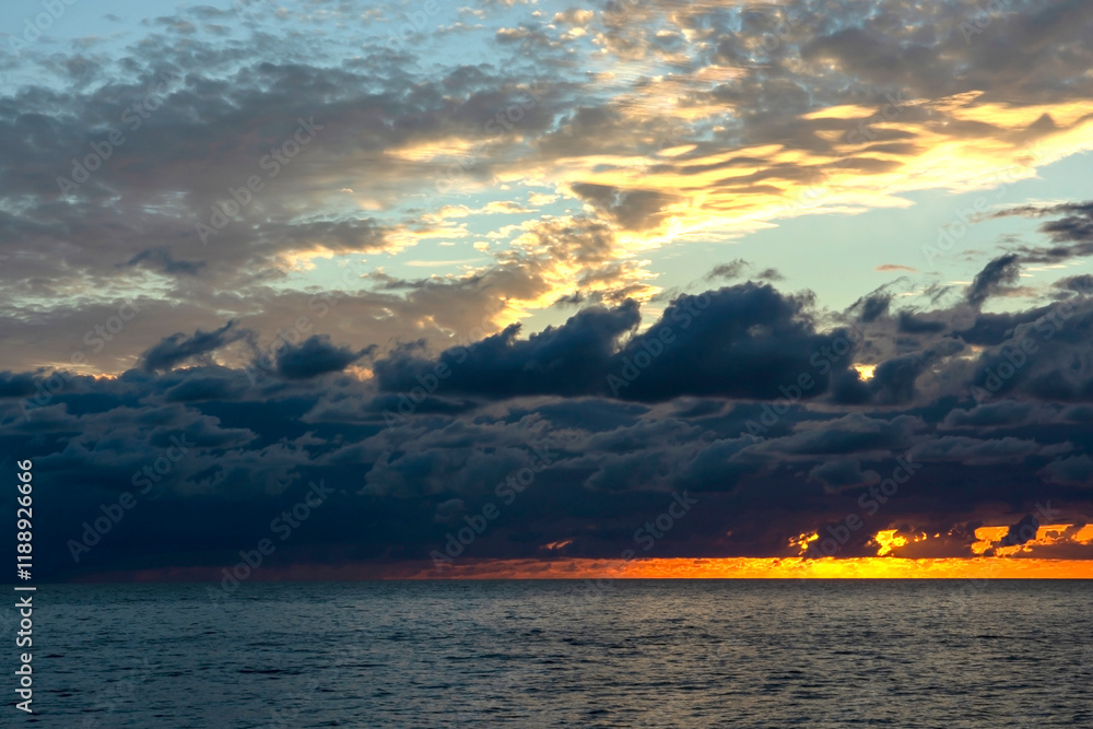 Fototapeta premium Red sunset over the sea, rich in dark clouds, rays of light. Black Sea coast, early autumn