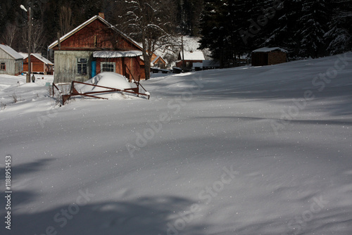 An old wooden house in a winter mountain village surrounded by fresh fluffy sparkling snow.