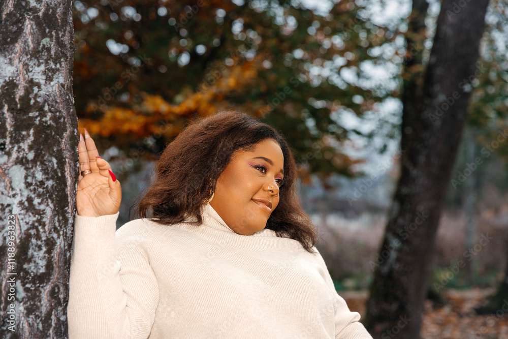 African adult female enjoying autumn nature in cozy sweater African adult female enjoying autumn nature in cozy sweater