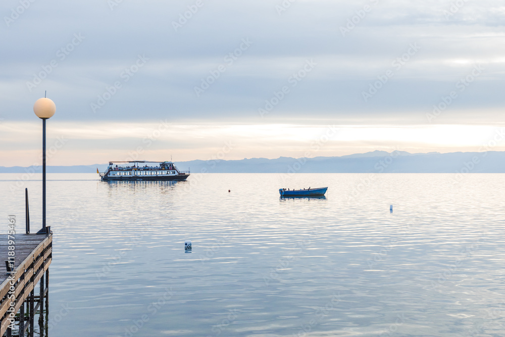 Sunset over lake, peaceful boats floating on still water with distant mountain views. Sunset over lake, peaceful boats floating on still water with distant mountain views.