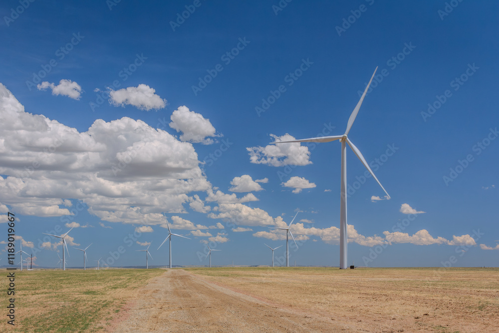 Photo of Windmill with three turbines, producing sustainable power energy or green energy by windblown. These windmills located in the rural flat dirt road landscape area, with white clouds blue sky . Photo of Windmill with three turbines, producing sustainable power energy or green energy by windblown. These windmills located in the rural flat dirt road landscape area, with white clouds blue sky .