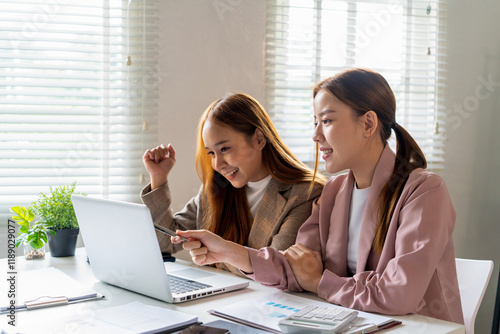 Businesswoman sitting at desk on couch in workplace or at home working on laptop and analyzing data on charts and graphs and writing on papers to make business plan and strategies for company.