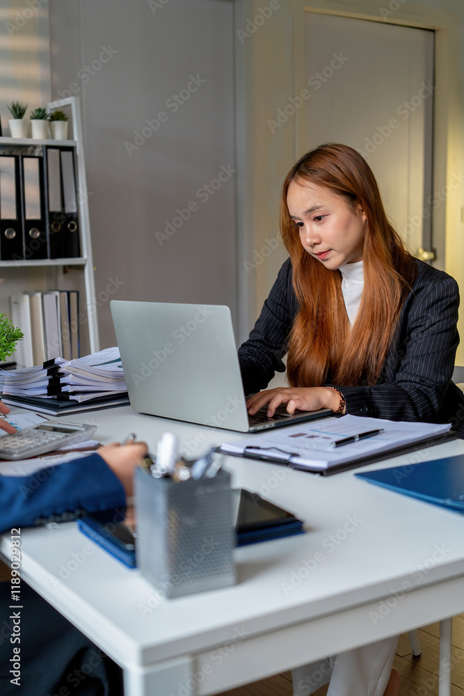 Businesswoman sitting at desk on couch in workplace or at home working on laptop and analyzing data on charts and graphs and writing on papers to make business plan and strategies for company. Businesswoman sitting at desk on couch in workplace or at home working on laptop and analyzing data on charts and graphs and writing on papers to make business plan and strategies for company.