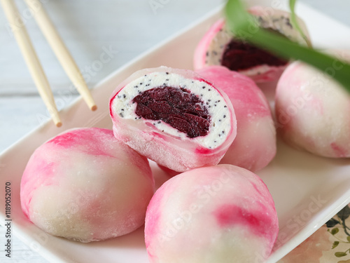 Delicious dessert featuring pink and white mochi filled with red bean and sesame cream served on a plate