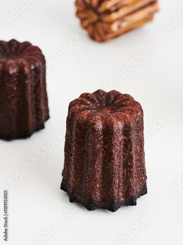 These caneles feature a rich, dark brown hue with a glossy surface. Their unique shape with ridges and caramelized edges makes them visually appealing, perfect for dessert lovers photo