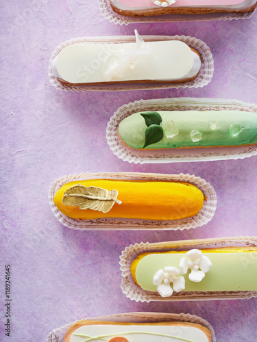 Beautifully crafted pastries in shades of yellow, green, and white are arranged on a vibrant purple surface. Each pastry showcases unique decorative elements and flavors photo