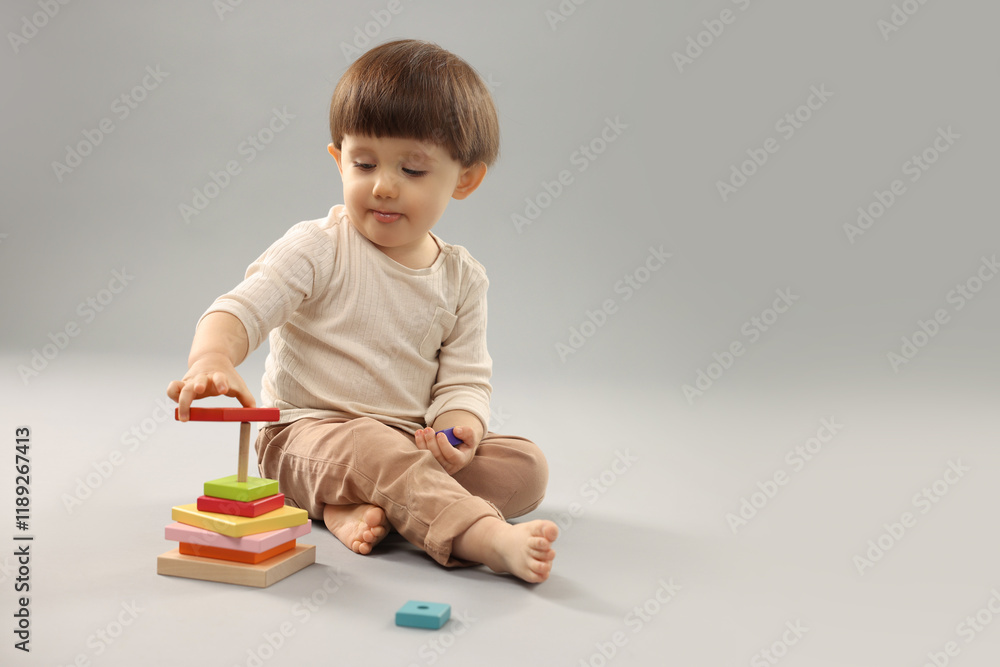 Cute little boy playing on grey background. Space for text Cute little boy playing on grey background. Space for text