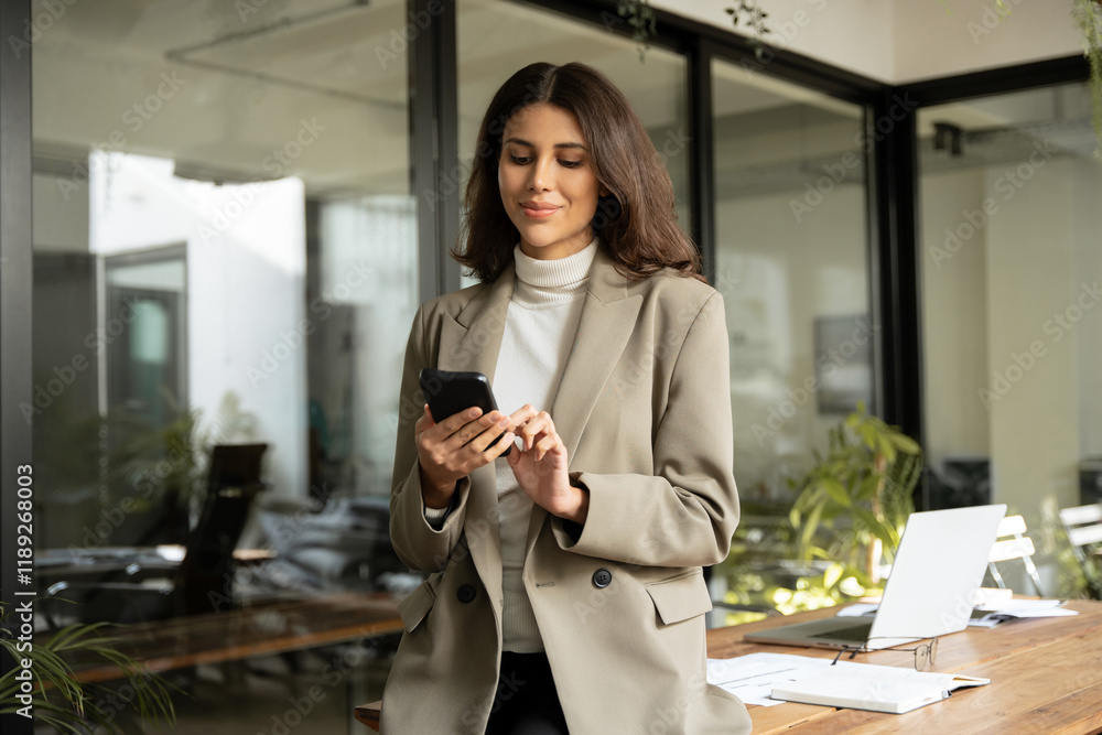 © Stock 4 You - Young Indian business woman manager ceo using cell phone mobile app laptop. Smiling Latin Hispanic mature female businesswoman holding smartphone in office trading, reading, working online. Copy space
