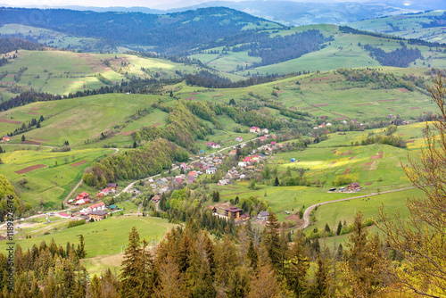 Obraz na płótnie Rolling hills embrace a tranquil village nestled in the valley at sunset w salonie