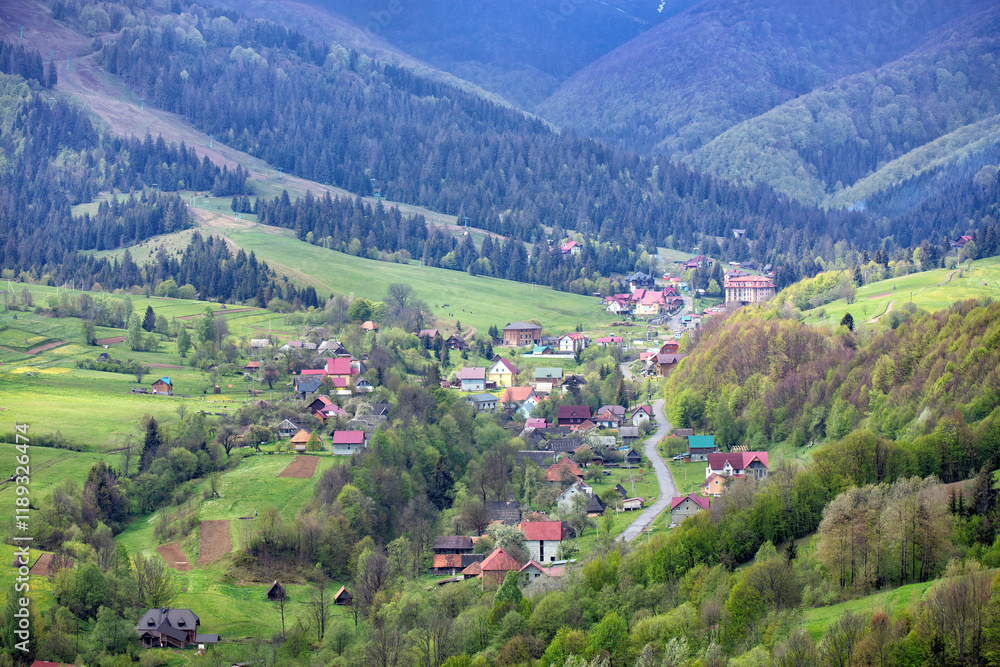 Peaceful village nestled among lush green mountains during a bright spring day