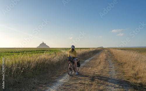 Bike and adventure in Mont Saint Michel. Female traveler pedals through rural area near Mont Saint Michel in France.