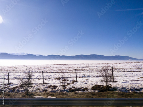 Obraz na płótnie View to field and mountain with fog and snow from highway w salonie