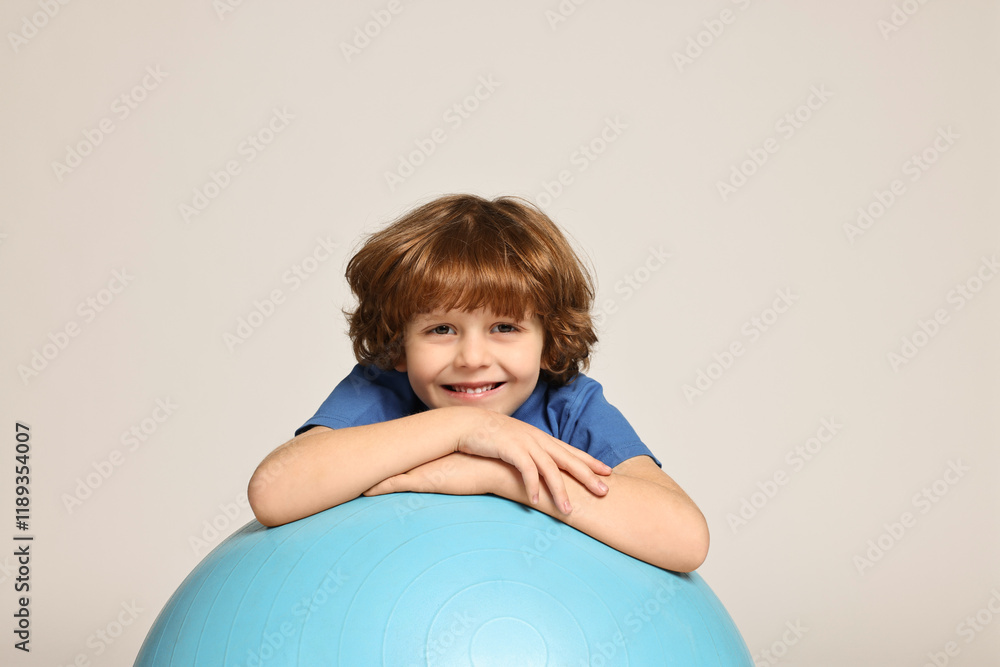 Little boy with fitness ball on light grey background Little boy with fitness ball on light grey background