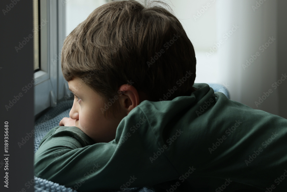 Autism concept. Lonely little boy near window at home Autism concept. Lonely little boy near window at home